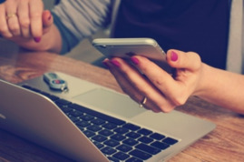 woman-text-messaging-with-laptop-on-wooden-table.jpg